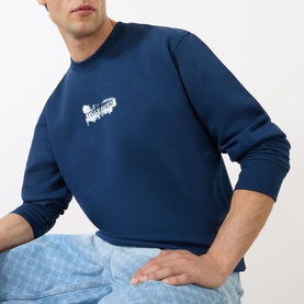 Model wearing Daily Paper Scratch Logo Sweatshirt in blue, crew neck with white graphic logo, styled with light blue jeans