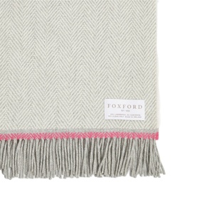 Foxford Lily Throw in grey herringbone with pink contrast edge trim, fringed ends, and woven logo badge detail