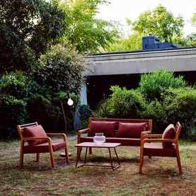 FERMOB Somerset Bench in Chili red with matching armchairs and low coffee table, styled in a garden setting with natural teak frames