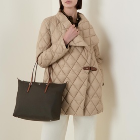 Model carrying Lauren Keaton Medium Tote Bag in olive nylon with silver-tone hardware, styled with a beige quilted coat and white trousers