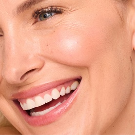 Model with TRINNY LONDON BFF De-Stress Tinted Serum in Claire, showing close-up of glowing, even complexion with natural finish