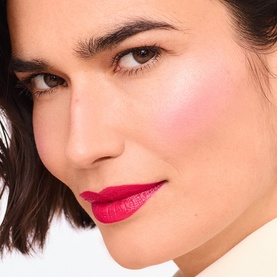 Model with TRINNY LONDON Lip2Cheek Colour in Milly, a rosy pink-red shade worn on lips and cheeks for a flushed, natural finish