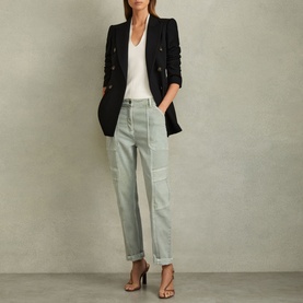 Model wearing Reiss Kimmy Knit Vest in white with deep V-neckline, styled with black blazer and light grey trousers