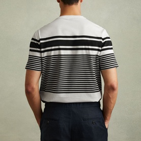 Model wearing Reiss Lory Striped T-Shirt in white with black stripes, crew neck, short sleeves, styled with navy trousers. Rear view