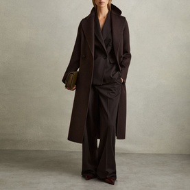 Model wearing Reiss Lucia Double-Breasted Coat in brown with oversized lapels and self-fabric belt, styled with matching wide-leg trousers