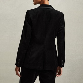 Model wearing Reiss Parisa Single-Breasted Velvet Blazer in black, rear view, showing vent, satin cuff accents and button detail