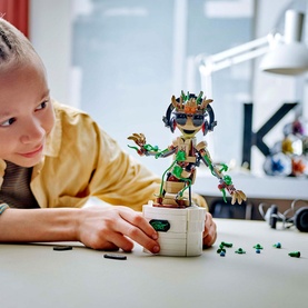Child building Lego Marvel Dancing Groot, a posable multi-coloured Groot figure with sunglasses, leaves and buildable accessories, on a desk