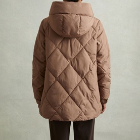 Model wearing Reiss Thea Diamond Quilted Coat in beige, back view showing diamond quilting, adjustable hood and dark trousers