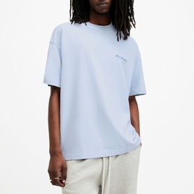 Model wearing All Saints Access Logo Oversized T-Shirt in blue, round neckline, short sleeves, small chest logo print, styled with grey joggers
