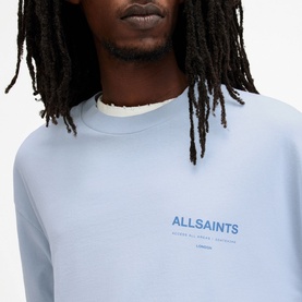 Model wearing All Saints Access Logo Oversized T-Shirt in blue, close-up showing chest logo print and round neckline
