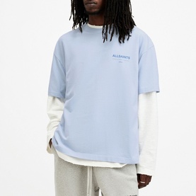 Model wearing All Saints Access Logo Oversized T-Shirt in blue, layered over white long-sleeve top, styled with grey marl joggers