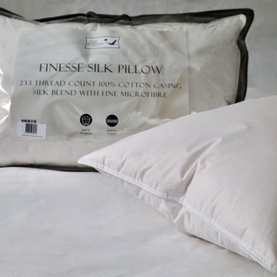 The Soft Bedding Co Silk Microfibre Pillow in white, shown with packaging and styled on a bed with white bedding