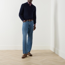 Model wearing Ralph Lauren Knitted Logo Long-Sleeved Polo Shirt in navy wool, styled with light blue jeans and brown loafers