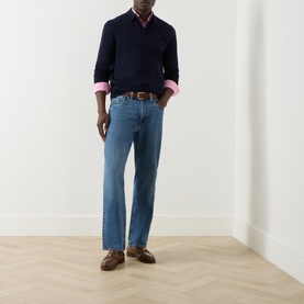 Model wearing Ralph Lauren Knitted Logo Long-Sleeved Polo Shirt in navy wool, styled with blue jeans, pink shirt and brown loafers