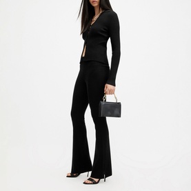 Model wearing All Saints Cruz Ribbed Black Cardigan with matching black flared trousers, black heels, carrying a small black box bag
