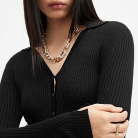 Model wearing All Saints Cruz Ribbed Black Cardigan with V-neckline and button fastenings, styled with chunky silver chain necklace and ring