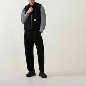 Model wearing Carhartt Logo Vest Gilet in black, styled with grey long-sleeve top and black trousers and chunky black boots