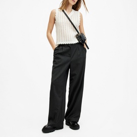 Model wearing All Saints Vivian Open-Stitch Knitted Vest in white with scalloped trims, styled with wide-leg black trousers and crossbody bag