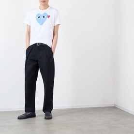 Model wearing Comme Des Gar&ccedil;ons Play Double-Heart Logo T-Shirt in white with blue heart graphic, styled with black wide-leg trousers and dark loafers.