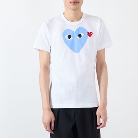 Model wearing Comme Des Garcons Play Double-Heart Logo T-Shirt in white with blue heart logo and red heart patch detail.