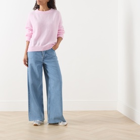 Model wearing AMERICAN VINTAGE Vitow Oversized Sweater in Dragee Chine with wide-leg light blue jeans and silver trainers.