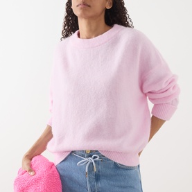 Model wearing American Vintage Vitow Oversized Sweater in Dragee Chine pink, ribbed trims, styled with blue jeans and pink bag.