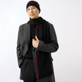 Model wearing Hugo Zaschel Two-Piece Hat and Scarf Set in black with red stripe detail, styled with a grey herringbone coat