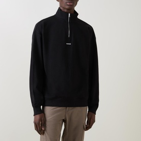 Model wearing Hugo Logo Half-Zip Sweatshirt in black with high neck, half-zip fastening and embroidered logo, styled with beige trousers