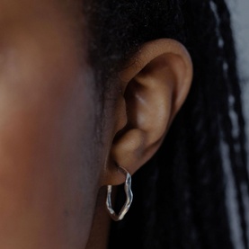 Model with Juvi Ripple Drop Hoops in silver sterling silver, featuring an organic curved open hoop design with push back fastening