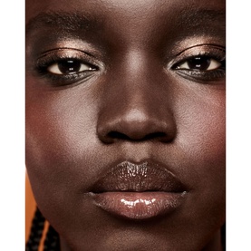 Model wearing FENTY Gloss Bomb Oil in Fro$ted Bunz, a sheer bronzed lip gloss, with warm copper eyeshadow
