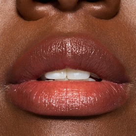 Close-up of lips wearing MAC Glow Play Tendertalk Lip Balm in a sheer rosy-brown shade with a glossy, hydrated finish