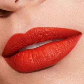 Est&eacute;e Lauder Pure Colour Explicit Silk Matte Lipstick in bold red-orange shade, close-up lip swatch showing matte finish