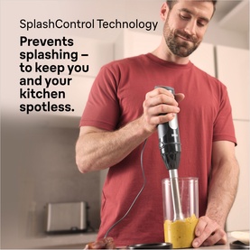Braun Multiquick 5 Stick Blender in black, held by man blending a yellow smoothie in a glass, kitchen setting