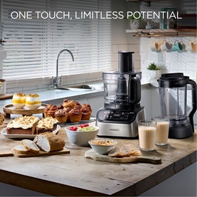 Kenwood Multipro Express Weighing & Direct Serve food processor in silver, styled in a kitchen setting with baked goods and smoothies