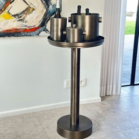 XL Boom Rondo Tray Table in black stainless steel, styled with matching black canisters on tray, abstract artwork in background
