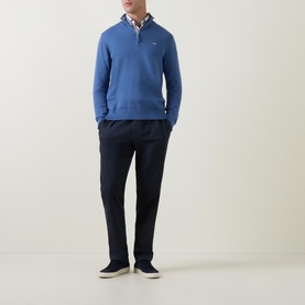 Model wearing Gant Shield Half-Zip Logo Sweater in blue with navy trousers and a check shirt underneath