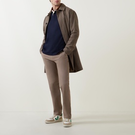 Model wearing Gant Navy Corduroy Collared Rugby Shirt with taupe trousers, brown overcoat and green-trim white trainers