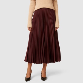 Model wearing Forever New Estelle High-Rise Pleated Skirt in burgundy, styled with a beige top and dark green heels