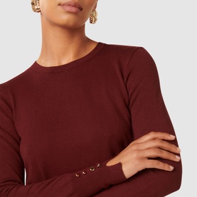 Model wearing Forever New Katie Split-Cuff Sweater in burgundy, showing gold button detail at split cuff and crew neckline