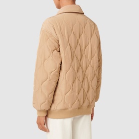 Model wearing Forever New Jacinta Quilted Jacket in brown, shown from behind, with classic collar, quilted texture, and ribbed hem