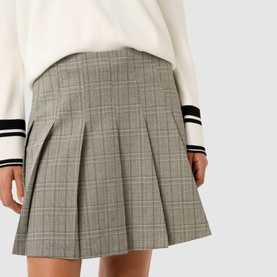 Model wearing Forever New Montana Pleated Mini Skirt in grey check with pleated detailing, styled with a white varsity-stripe sweater