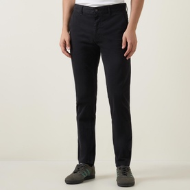 Model wearing Hugo Boss Orange Slim-Leg Chinos in black, slim mid-rise fit with belt loops, styled with grey trainers