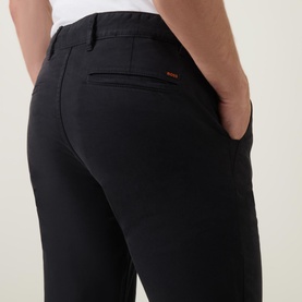 Model wearing Hugo Boss Orange Slim-Leg Chinos in black, showing rear welt pocket with orange logo detail