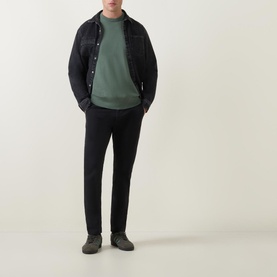 Model wearing Hugo Boss Orange Slim-Leg Chinos in black, styled with a dark denim jacket and green sweatshirt
