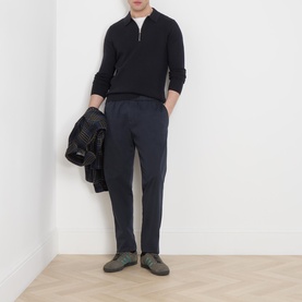 Model wearing Samsoe & Samsoe Guna Half-Zip Sweater in navy, styled with navy trousers and grey shoes, holding a dark jacket