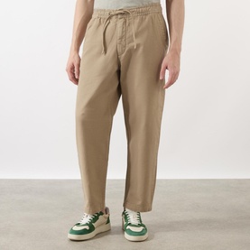 Model wearing Wax London Kurt Drawstring Casual Trousers in khaki with elasticated waist, styled with green and white trainers