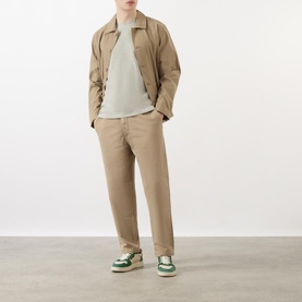 Model wearing Wax London Kurt Drawstring Casual Trousers in khaki, styled with a light grey tee, beige overshirt and green trainers
