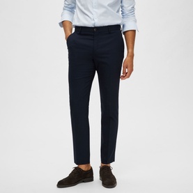 Model wearing Selected Neil Suit Trousers in navy, slim-cut with pressed creases, styled with a light blue shirt and brown suede shoes