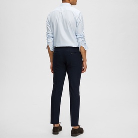 Model wearing Selected Neil Suit Trousers in navy, slim-cut with pressed creases, styled with a light blue shirt and dark shoes, rear view