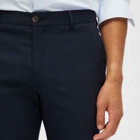 Model wearing Selected Neil Suit Trousers in navy, slim-cut with button fastening and belt loops, styled with a light blue shirt